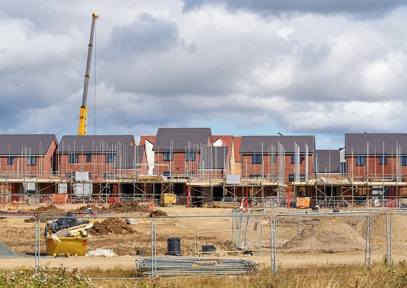 A group of houses under construction with a crane in the background.