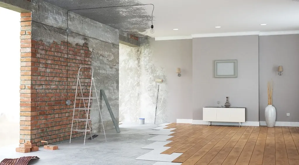 A room is being remodeled with wood floors and a brick wall.