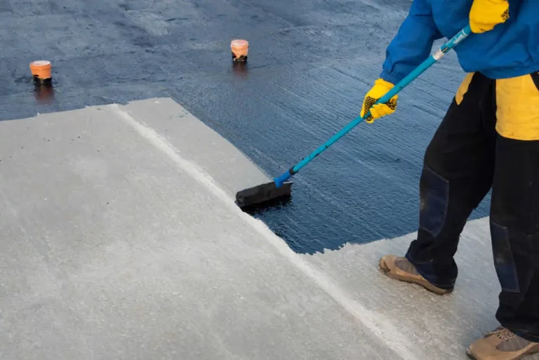A man using a broom to clean a concrete surface commercial roofing.
