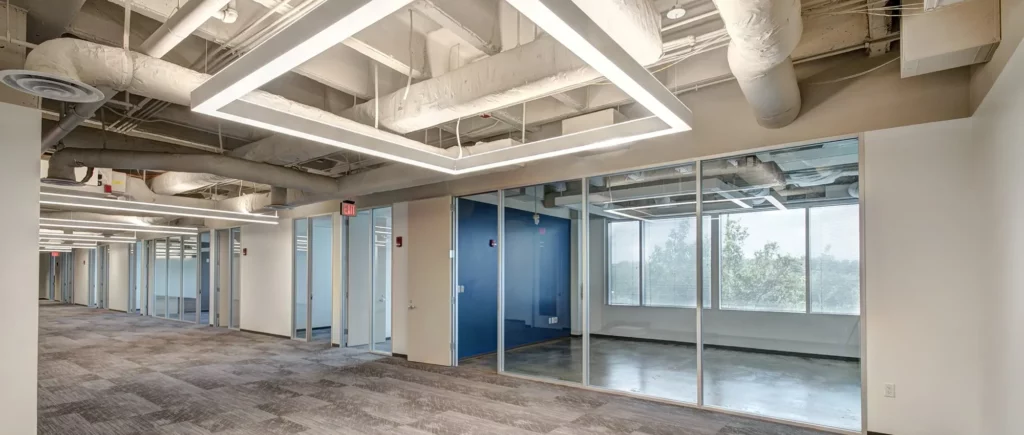 A hallway in an office with blue carpet and glass windows commercial tenant improvement San Francisco.