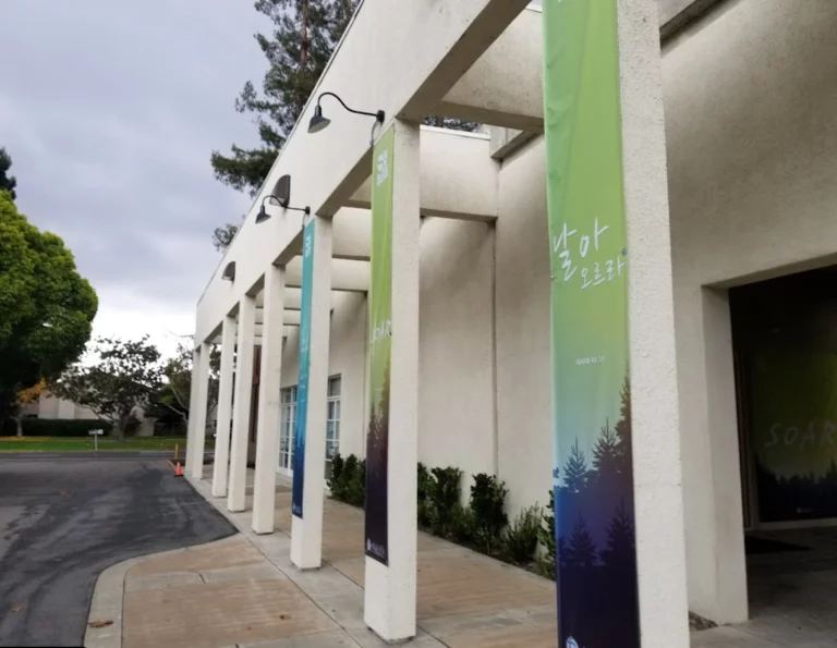 A church building constructed by an institutional contractor with several banners on the side of it.