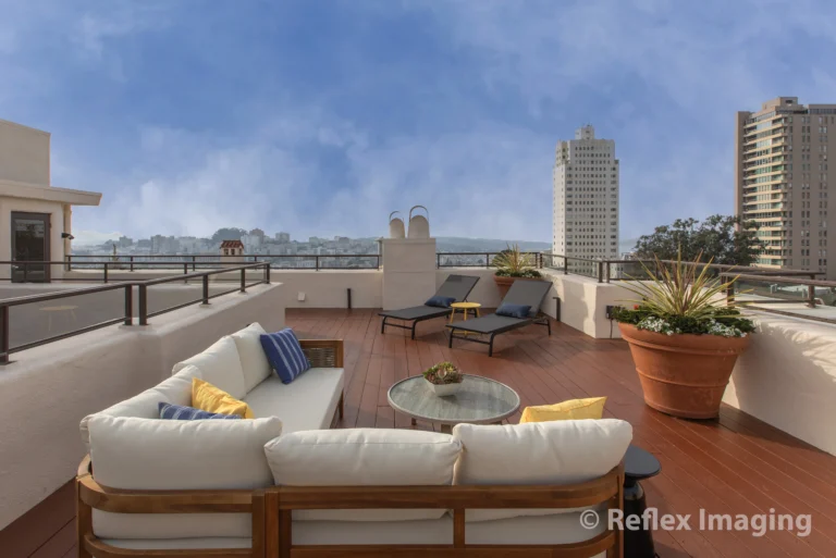 A rooftop deck with furniture and a view of the city.