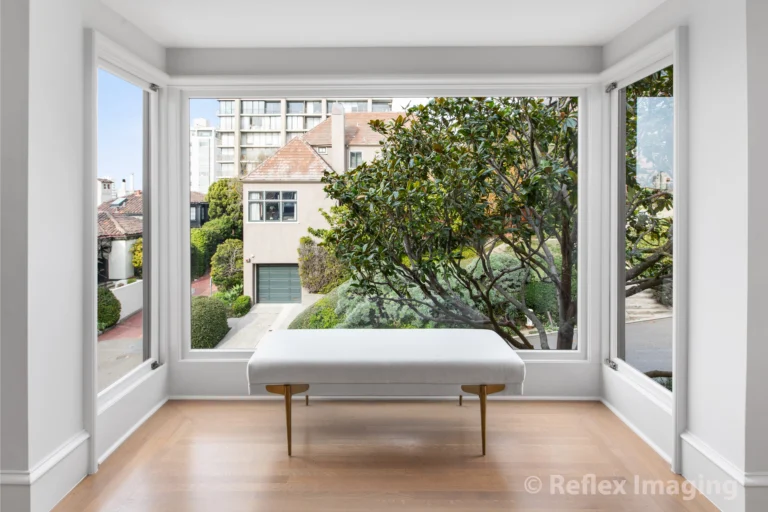 A white bench sits in front of a window in a room.