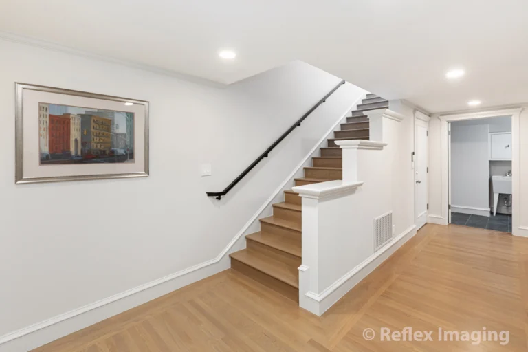 A hallway with stairs leading to a room with a painting.