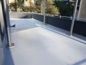 Bay Area waterproofing on a white tiled roof with a metal railing.