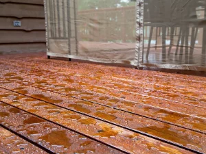 A wooden deck with water droplets on it Bay Area waterproofing.