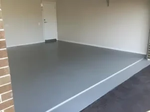 Concrete contractors complete a garage with a grey floor and a brick wall.